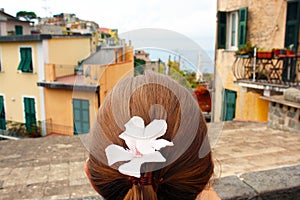 A beautiful woman with a pink flower in her hair looking over the beautiful city of Corniglia in Cinqueterre, Italy