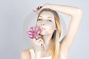 Beautiful woman with pink flower and her hand raised. Waxing armpit. Epilation result.
