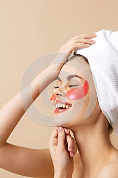 beautiful woman pink patches on the face with a towel on the head beige background