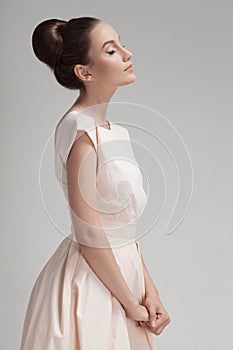 Beautiful woman in pink retro dress. Gray background.