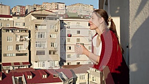 Beautiful woman in plaid drinking coffee while looking through window on city. People relaxing, resting at home.