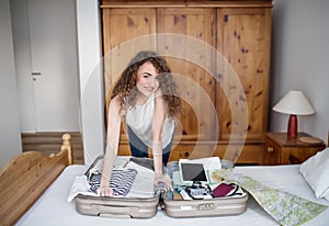 Beautiful woman planning summer vacation abroad, sitting on floor, packing suitcase. Solo traveler.