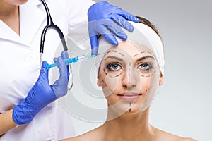 Beautiful woman with plastic surgery, plastic surgeon holding a needle