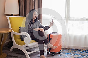 A beautiful woman is playing on her cellphone near her suitcase