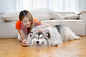 beautiful woman playing with her dog in room at home happily