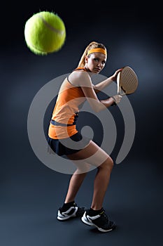 Beautiful woman playing padel indoor. on black. photo