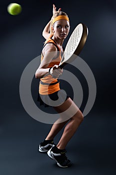 Beautiful woman playing padel indoor. on black. photo