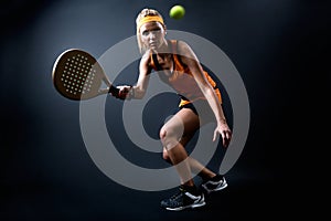 Beautiful woman playing padel indoor. Isolated on black. photo