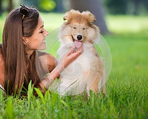 Beautiful woman playing in the park with a puppy collie