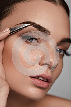 Beautiful Woman Plucking Eyebrows. Beauty Brows Correction photo