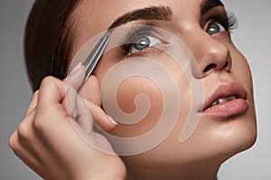 Beautiful Woman Plucking Eyebrows. Beauty Brows Correction photo