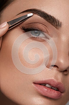 Beautiful Woman Plucking Eyebrows. Beauty Brows Correction photo