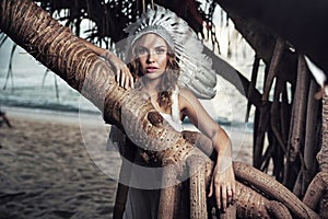 Beautiful woman with a plume leaning against the branch