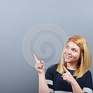 Beautiful woman pointing to blank area against  gray background