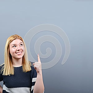 Beautiful woman pointing to blank area against  gray background