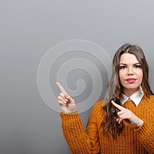 Beautiful woman pointing to blank area against  gray background