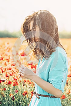 Beautiful woman with poppy flower in the meadow.