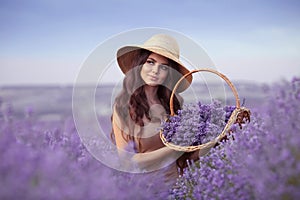 Beautiful woman portrait in lavender field  in Provence. Attractive girl with long curly hair in straw hat  holding violet flowers