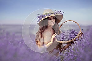 Beautiful woman portrait in lavender field  in Provence. Attractive girl with long curly hair in straw hat  holding violet flowers