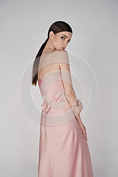 Beautiful woman pose in studio in pink classic dress