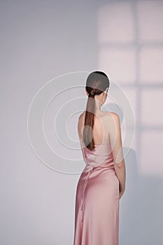 Beautiful woman pose in studio in pink classic dress