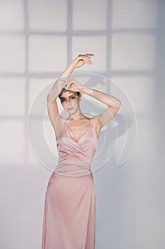 Beautiful woman pose in studio in pink classic dress