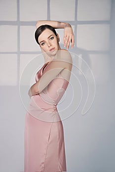 Beautiful woman pose in studio in pink classic dress