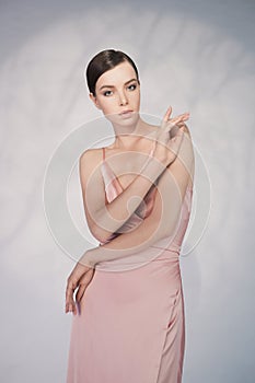 Beautiful woman pose in studio in pink classic dress