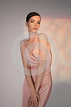 Beautiful woman pose in studio in pink classic dress