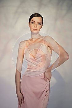 Beautiful woman pose in studio in pink classic dress