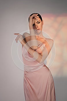 Beautiful woman pose in studio in pink classic dress