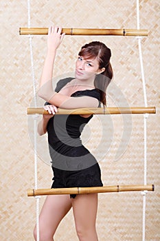 Beautiful woman poses holding bamboo rope ladder.