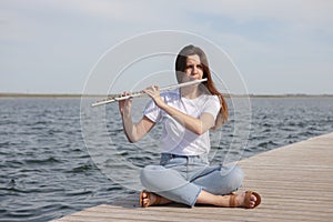 A beautiful woman posing in beach while playing on a flute