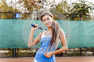 Beautiful woman posing on a clay tennis court after the game. An attractive, sexy lady in a short tennis skirt holding a racket