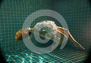 Beautiful woman posing underwater in white dress