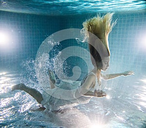 Beautiful woman posing underwater in white dress