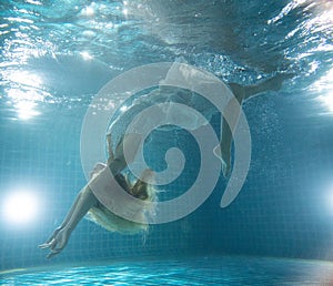 Beautiful woman posing underwater in white dress