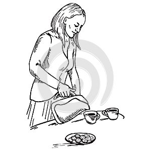 Beautiful woman pouring tea in cups, which stand on the table near plate with cookies