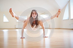 Beautiful woman practices handstand yoga asana Tittibhasana - firefly pose in the yoga studio