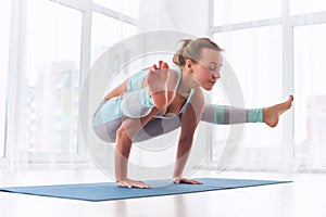 Beautiful woman practices handstand yoga asana Tittibhasana - firefly pose at the yoga studio