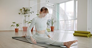 A beautiful woman practices a spagat exercises in bright studio, Anjaneyasana