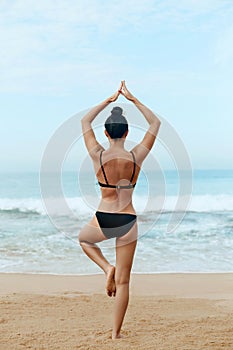 Beautiful woman practices yoga and meditates on th ebeach. Girl doing yoga.