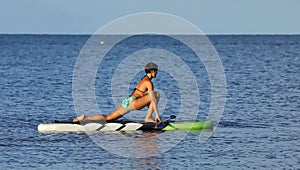 Beautiful woman practices yoga on a stand up paddle board.