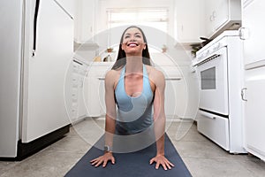 Beautiful woman practicing yoga, exercising in small home room kitchen, tiny home, cramped apartment