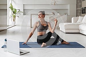 Beautiful woman practicing yoga at home by video lesson