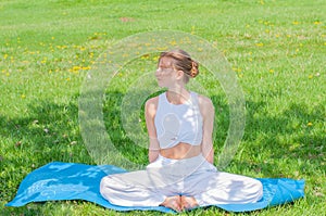 Beautiful woman is practicing yoga sitting in Lotus pose on grass