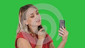 Beautiful woman preen using her phone like a mirror on a Green Screen, Chroma Key.