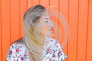Beautiful woman profile side portrait with long hairs blonde posing outdoor in orange wooden background