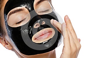 Beautiful woman with a purifying black mask on her face