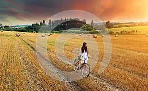 Beautiful woman pushes old red bike in a wheat field